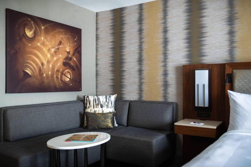 Modern hotel room with bed, couch, and abstract wall art